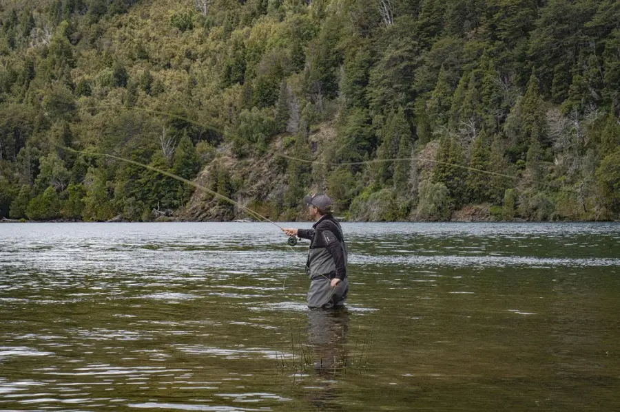 Fly angler casting on a calm forest lake
