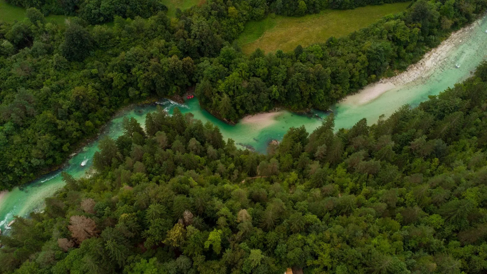 Aerial view of the emerald Soča river winding through forest near Tolmin, Slovenia