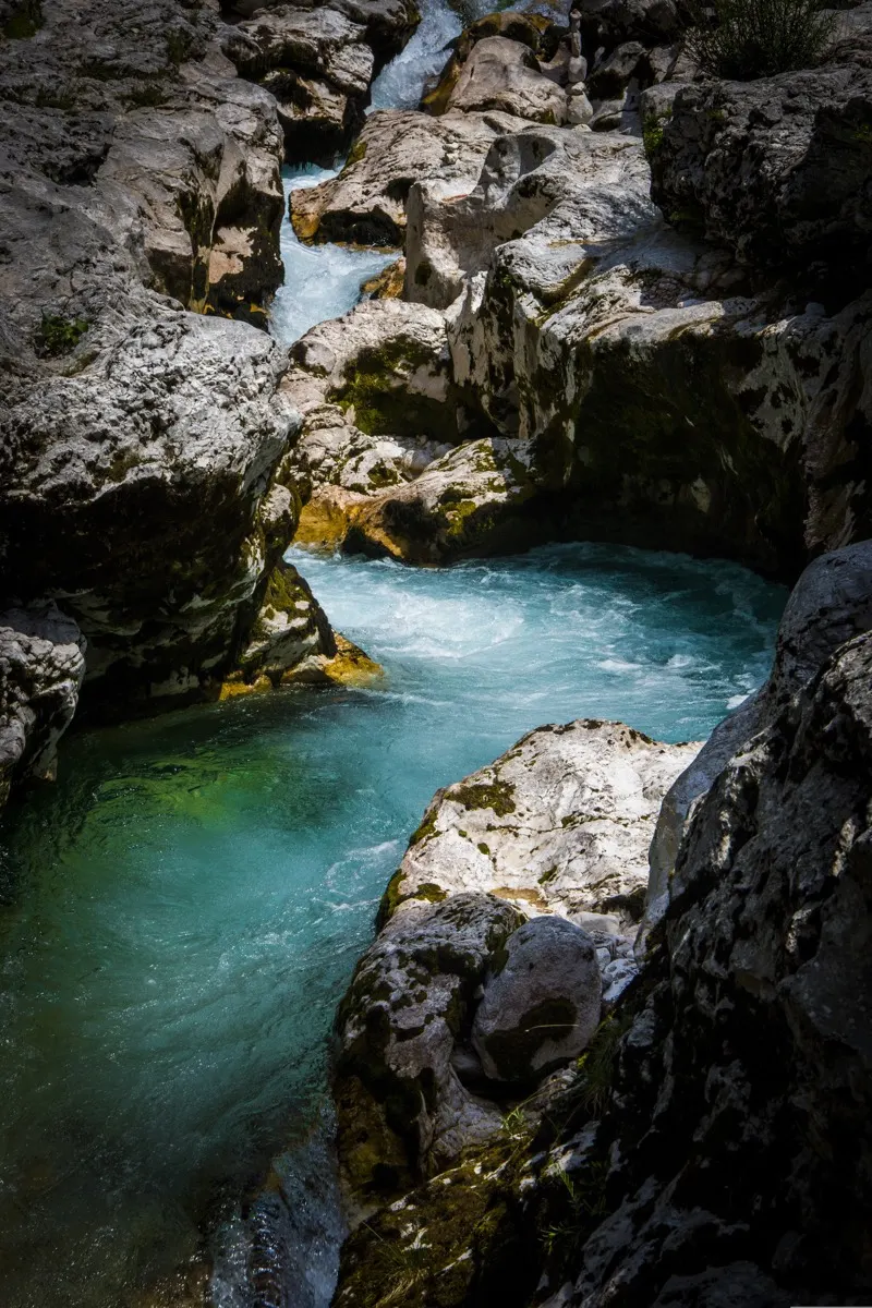 White water rapids running between limestone boulders into an emerald pool, Soča river, Slovenia