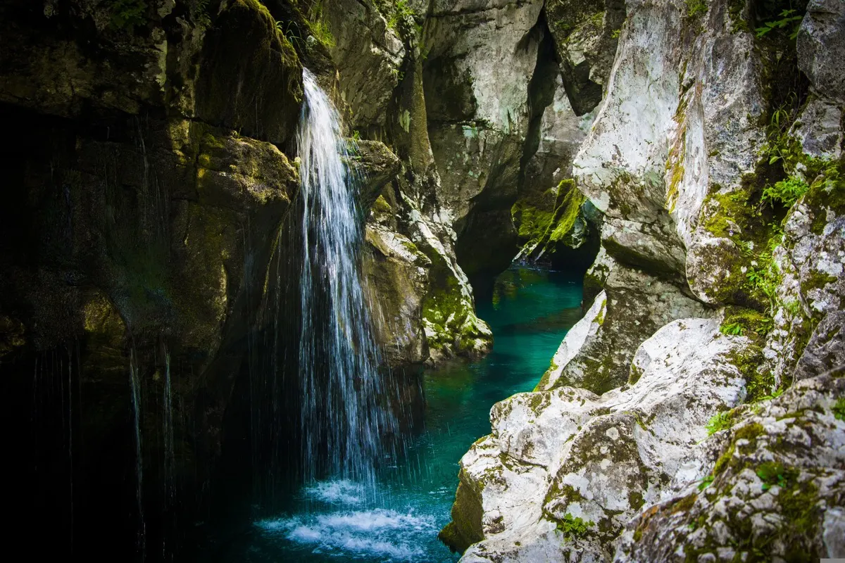 Waterfall pouring into an emerald pool in the Great Soča Gorge, Slovenia
